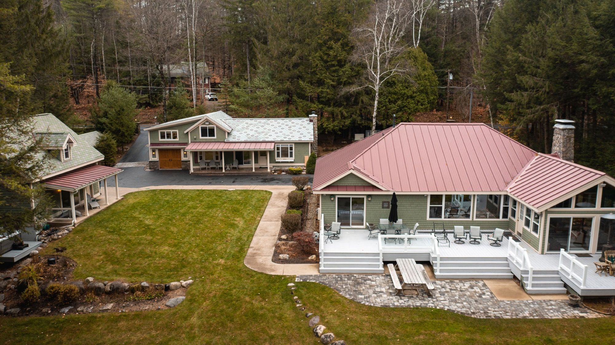 Aerial view of the main house and guest house at Camp Sunnyside, joined by the back lawn.
