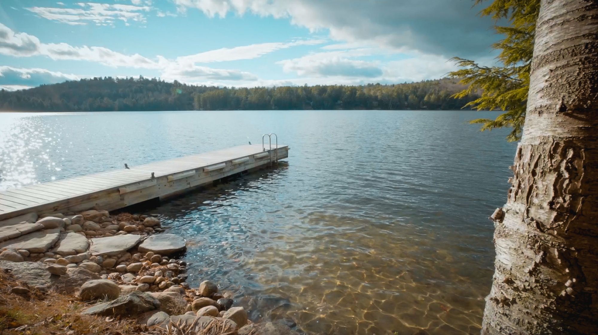 The swim dock on Friends Lake at Camp Sunnyside, with clear water over a rocky shallow.