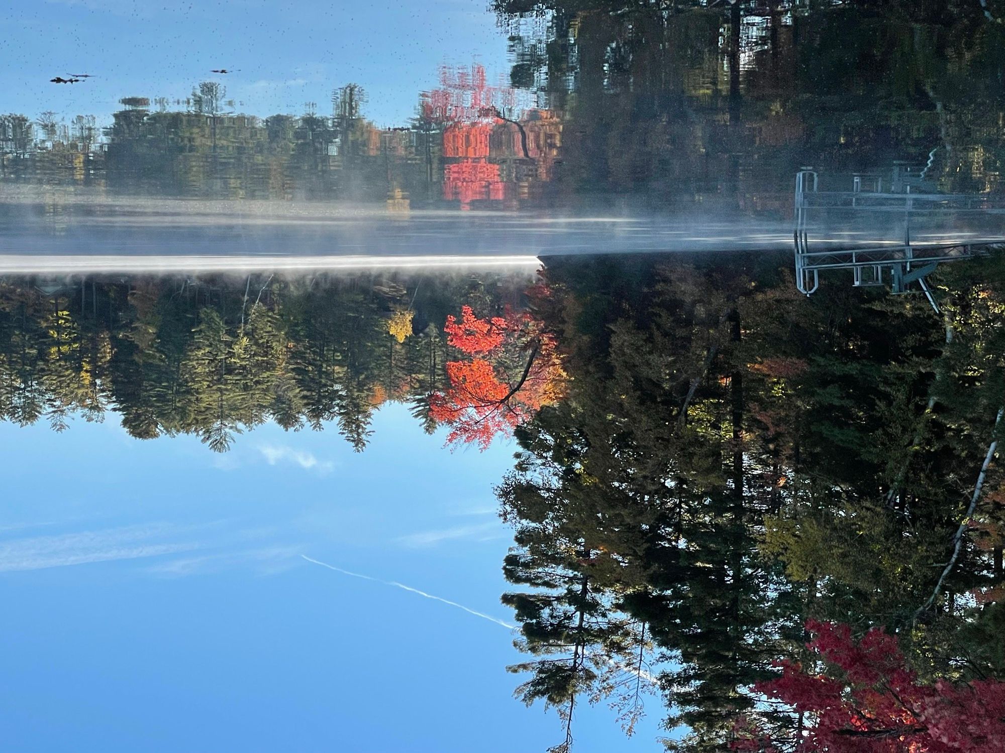 Morning mist on Friends Lake at Camp Sunnyside, with maples turning red along the shore.