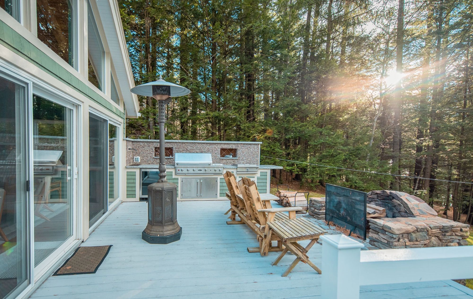 Golden-hour light on the back deck at Camp Sunnyside, with the outdoor kitchen and stone fire pit.
