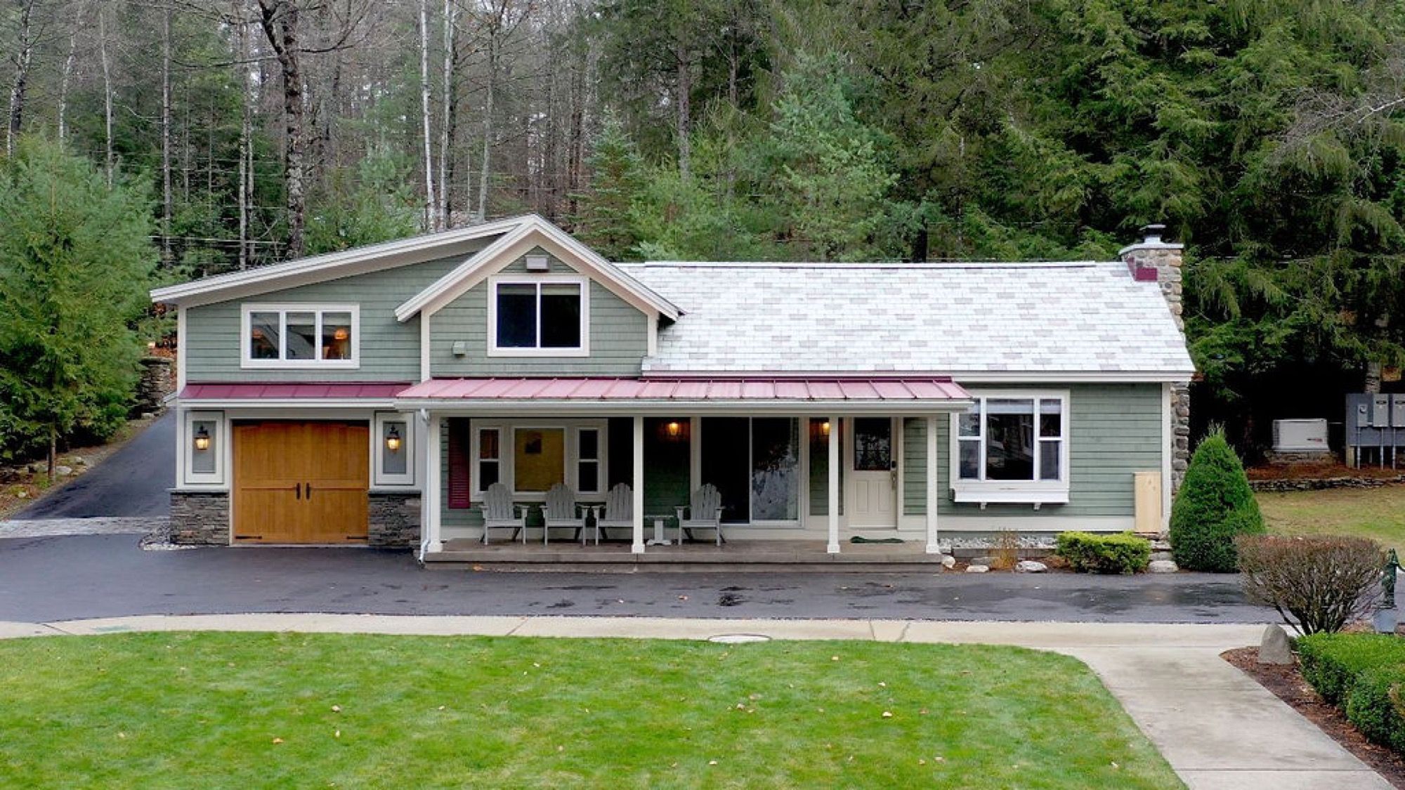 The front porch of the main house at Camp Sunnyside with a row of Adirondack chairs.
