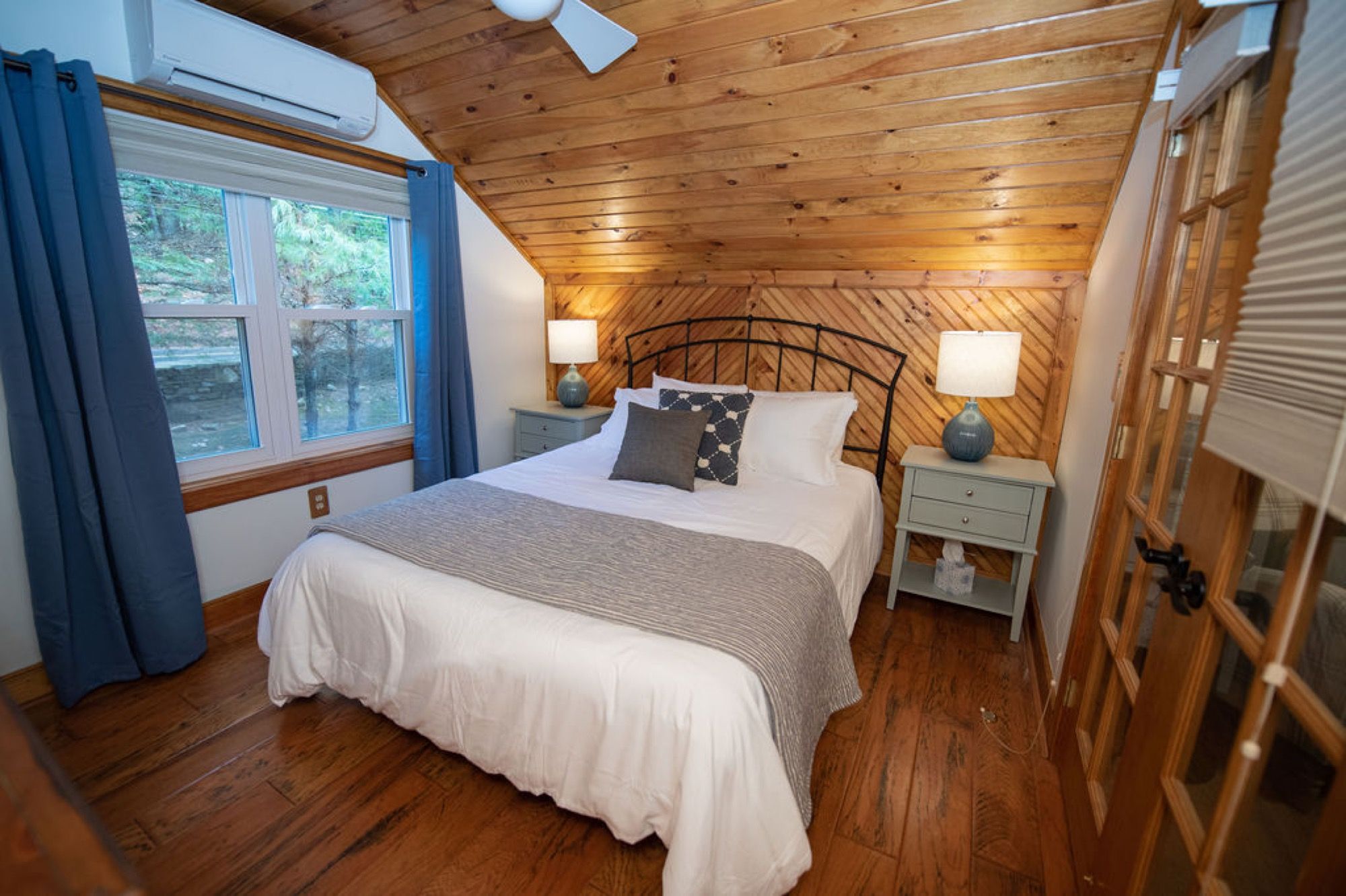 A queen bedroom under the wood ceiling in the guest house at Camp Sunnyside.
