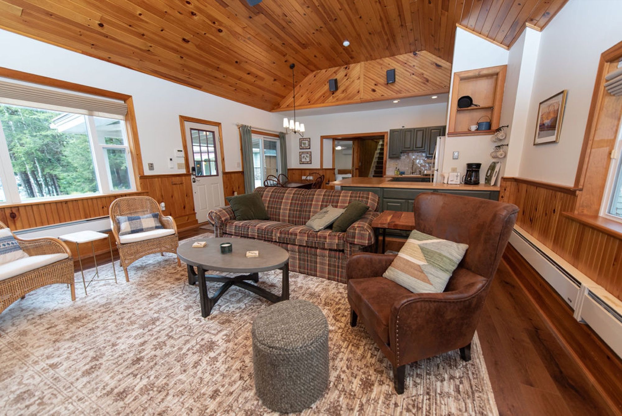 The guest house living room and kitchen at Camp Sunnyside under a vaulted pine ceiling.