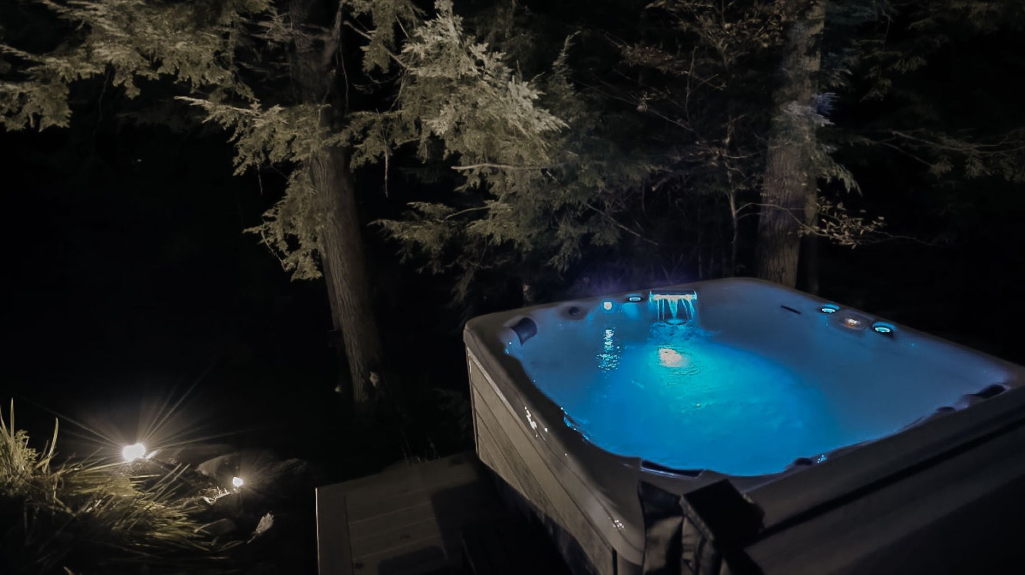 The hot tub at Camp Sunnyside glowing at night among the pines.
