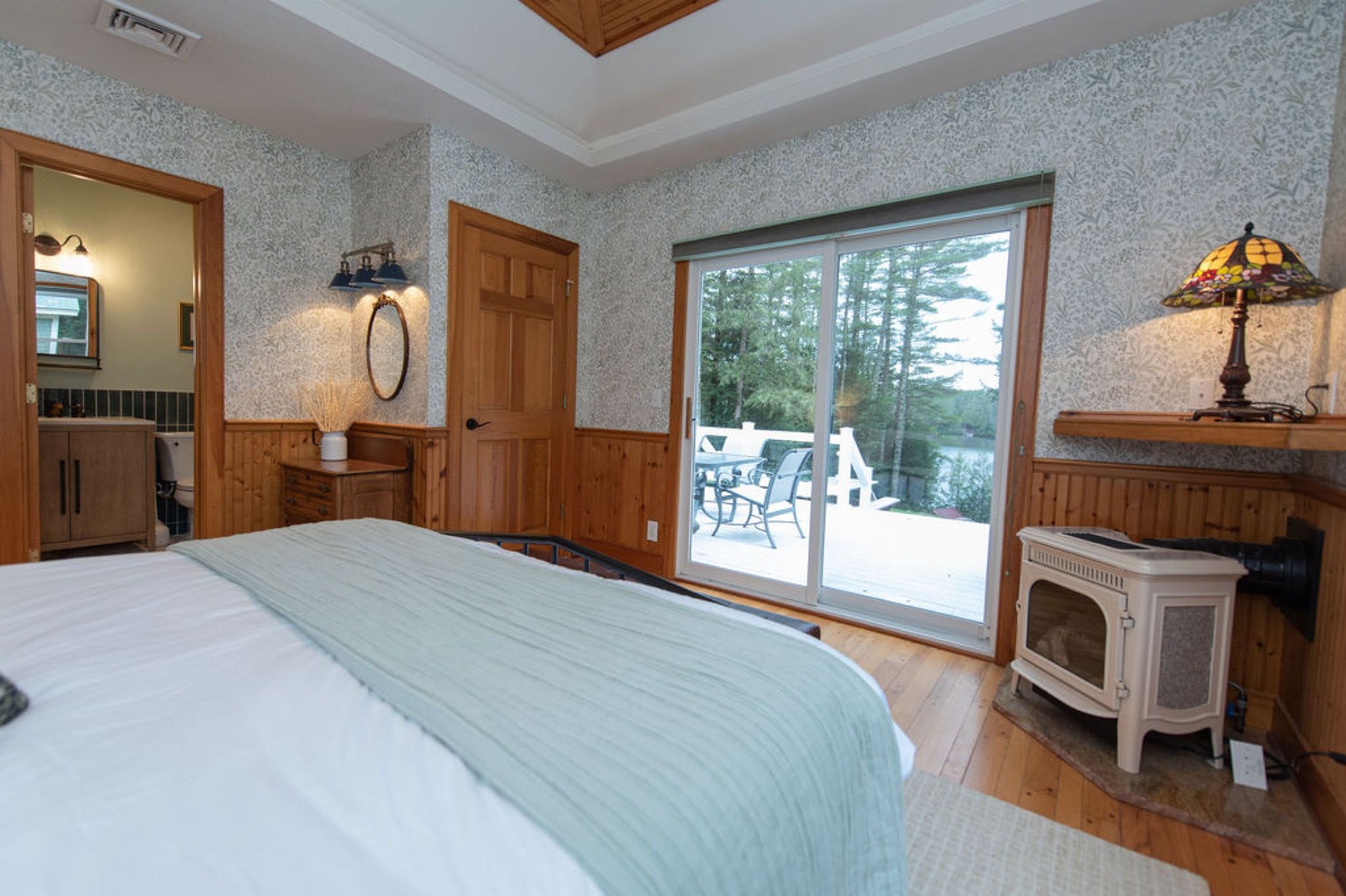 A bedroom at Camp Sunnyside with sliding doors to the deck and a view of Friends Lake.