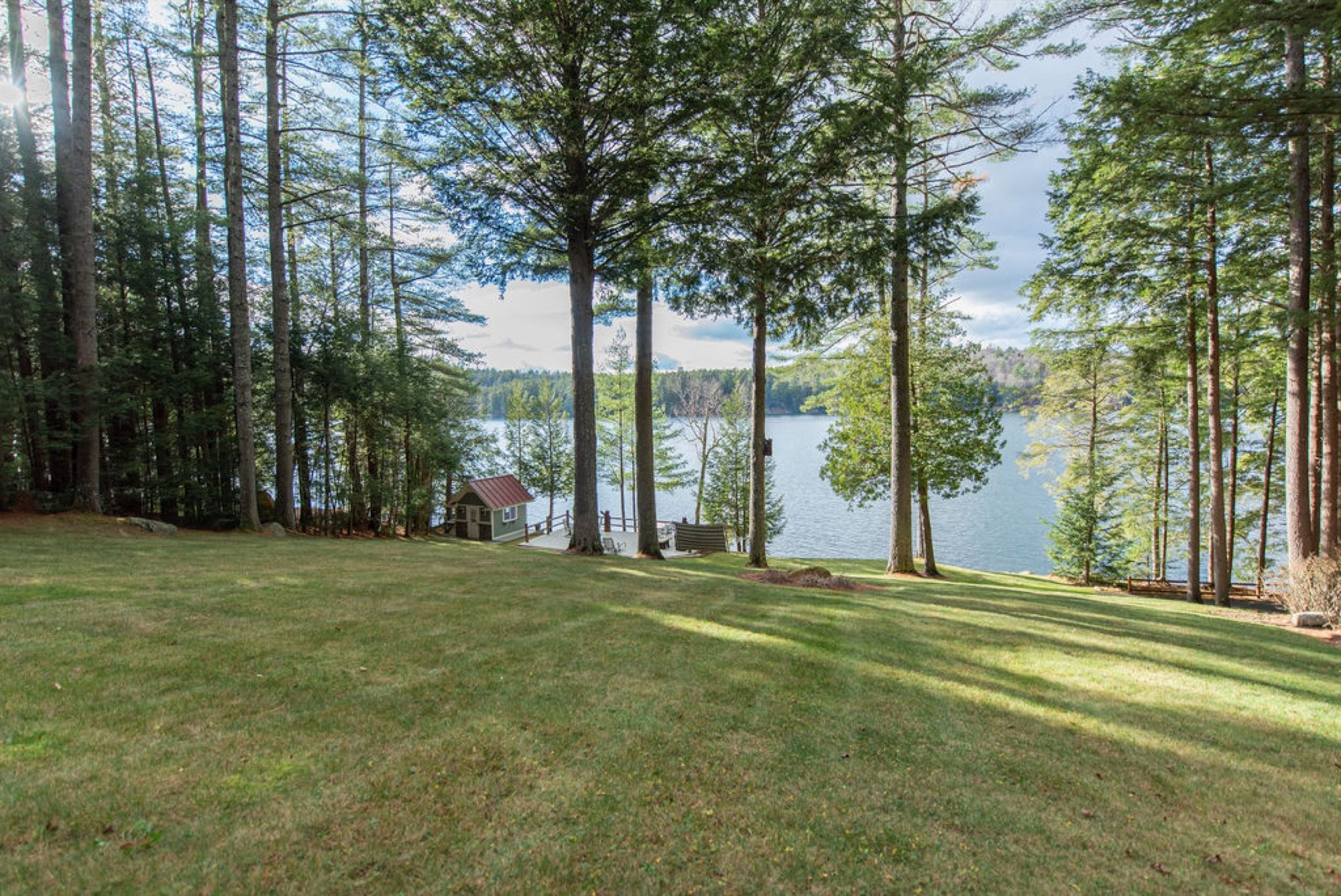 The lawn at Camp Sunnyside sloping through tall pines to the boathouse and Friends Lake.