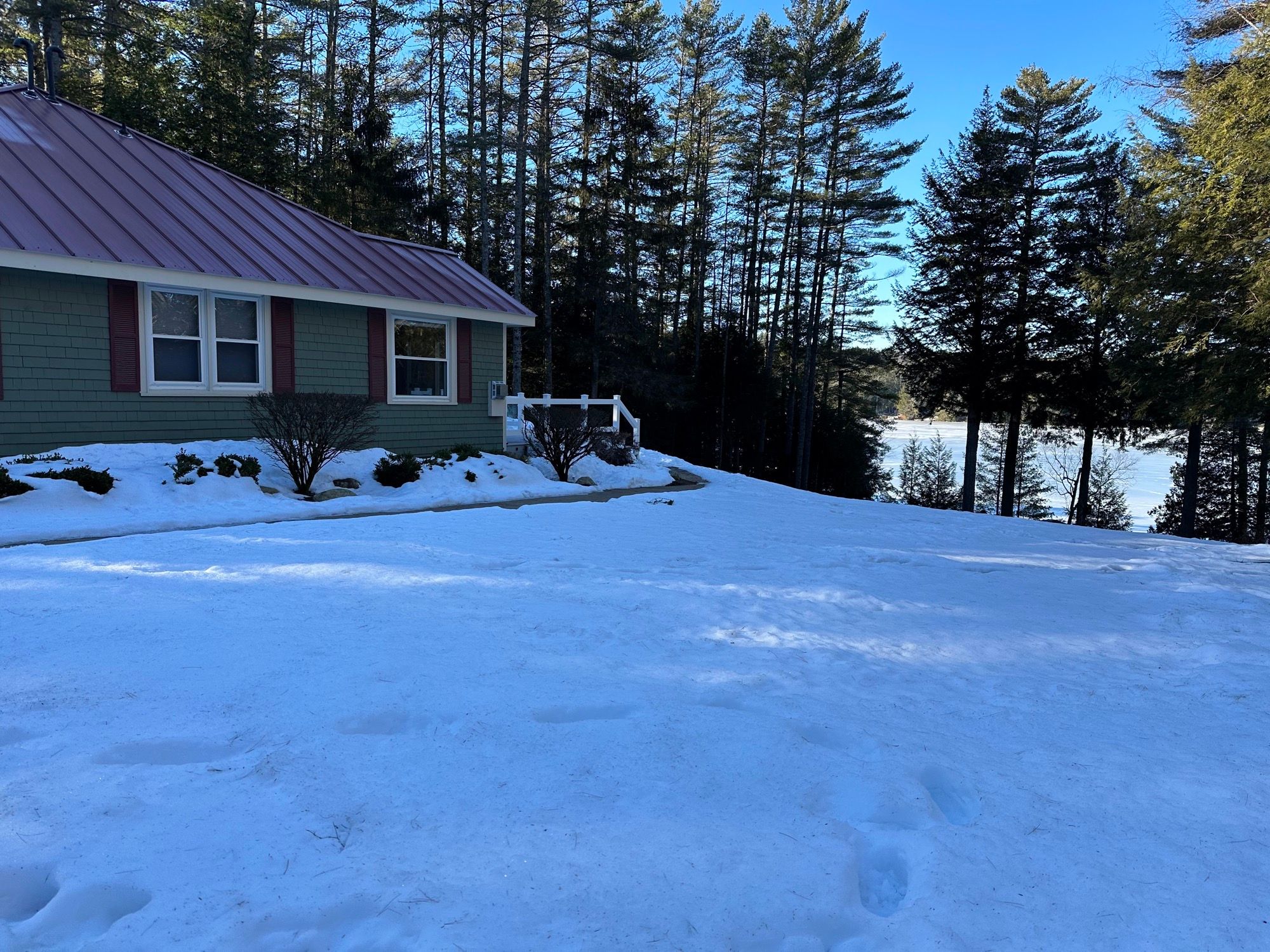 The guest house at Camp Sunnyside in winter, with snow on the ground and the frozen lake through the trees.